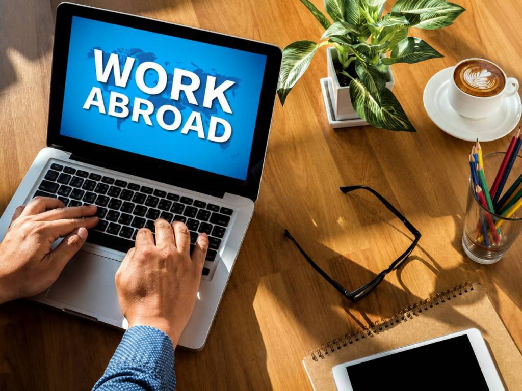 Laptop showing "Work Abroad" on screen with someone exploring overseas employment opportunities.